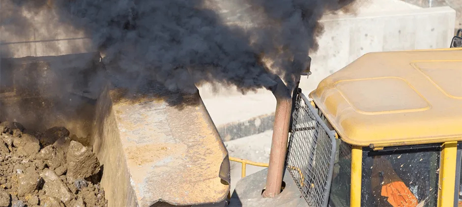 Heavy construction equipment emitting a thick plume of black smoke from its exhaust stack, which indicates a fuel system issue, not oil burning.