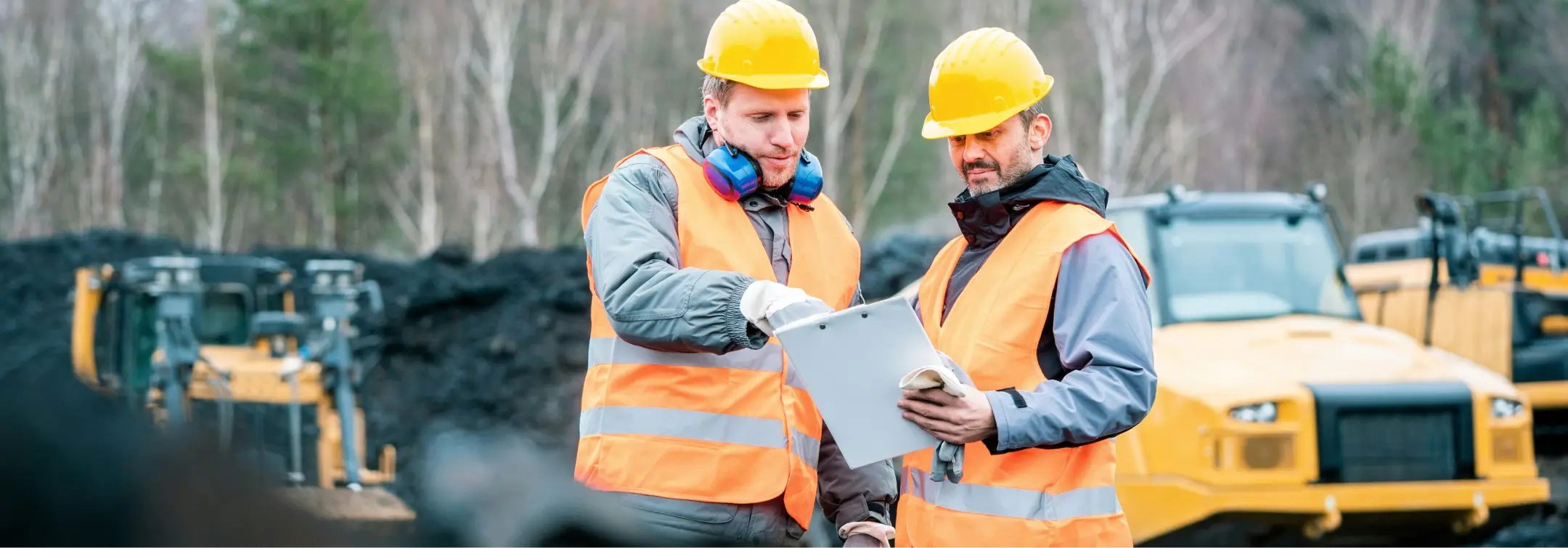 Two-workers-checking-work-at-a-construction-site-with-heavy-construction-machinery-in-the-background