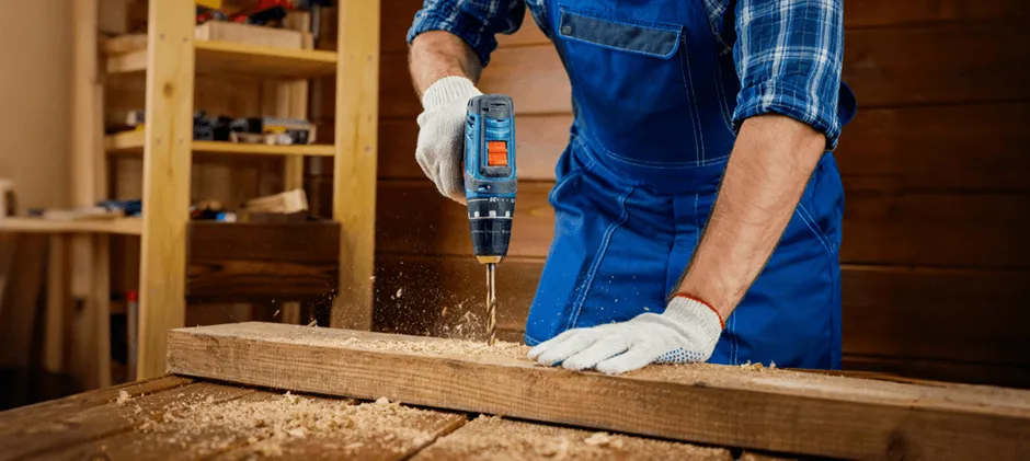 A cordless drill driver creating a clean hole in a wooden plank, demonstrating its core function of precise drilling.