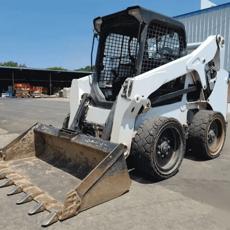 A white skid steer with a toothed bucket attachment parked on an asphalt surface, highlighting its wheeled undercarriage.