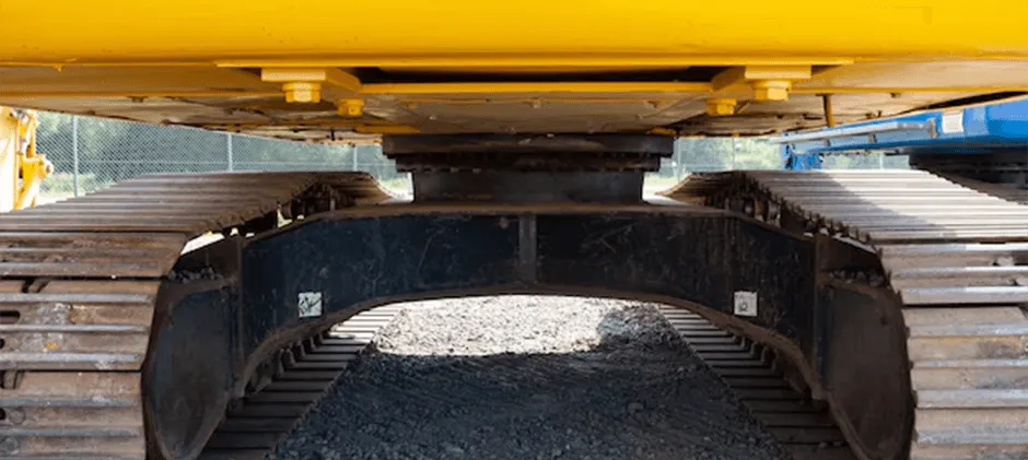 Close-up view of an excavator's slew bearing mounted between the upper house and the track undercarriage.