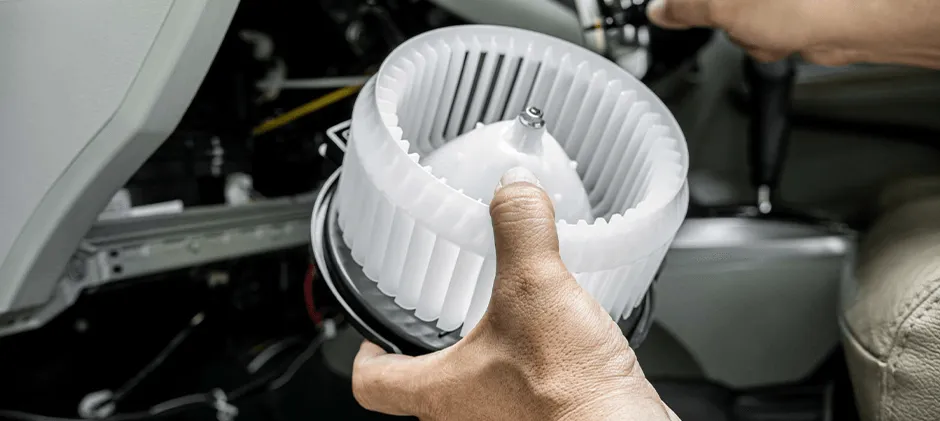 A person is holding the blower motor, with the picture focusing on the enlarged close-up of the blower motor.